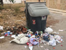 Contenedor rodeado de basura.