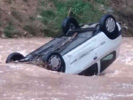 Coche arrastrado por el agua de un barranco.