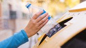 Una persona recicla una botella en el contenedor amarillo.